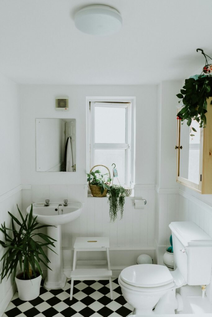 Dans l'univers de la décoration intérieure, la salle de bain est souvent un espace négligé, mais avec quelques touches simples, elle peut devenir un véritable havre de paix. La salle de bain présentée ici est un parfait exemple de comment les éléments de design peuvent transformer un espace fonctionnel en un lieu de détente et de style. L'utilisation de couleurs neutres et de matériaux naturels crée une ambiance apaisante qui invite à la relaxation. Le blanc dominant des murs et des sanitaires reflète la lumière naturelle, rendant la pièce lumineuse et aérée. La présence de plantes vertes ajoute une touche de vitalité et de fraîcheur, renforçant l'impression de calme et de sérénité. Le sol, avec son damier de carreaux noirs et blancs, offre un contraste audacieux qui ancre l'espace et lui donne du caractère. Cette touche graphique simple mais efficace est un moyen facile d'ajouter de l'élégance à une pièce sans surcharger la décoration. L'équipement sanitaire classique, comprenant une baignoire sur pieds, évoque une nostalgie subtile qui rappelle les anciennes maisons de charme. Cet aspect vintage est très recherché pour ceux qui souhaitent combiner confort moderne et esthétique rétro. Pour ceux qui aiment ajouter un côté pratique à l'esthétique, l'intégration d'un miroir fonctionnel et d'étagères discrètes pour les essentiels de toilette garantit que la fonctionnalité ne cède pas la place à la forme. Ces éléments sont essentiels pour maintenir l'ordre et la propreté dans un espace souvent utilisé. En termes de décoration, moins est souvent plus. Ce principe est parfaitement illustré ici, où la simplicité du design contribue à une atmosphère relaxante qui transforme les routines quotidiennes en moments de zen. Cette approche minimaliste mais chaleureuse de la décoration de la salle de bain prouve que vous n'avez pas besoin de rénovations coûteuses ou de grands espaces pour créer un lieu à la fois fonctionnel et élégant. Juste quelques choix judicieux en matière de couleurs, matériaux et agencement peuvent faire toute la différence.